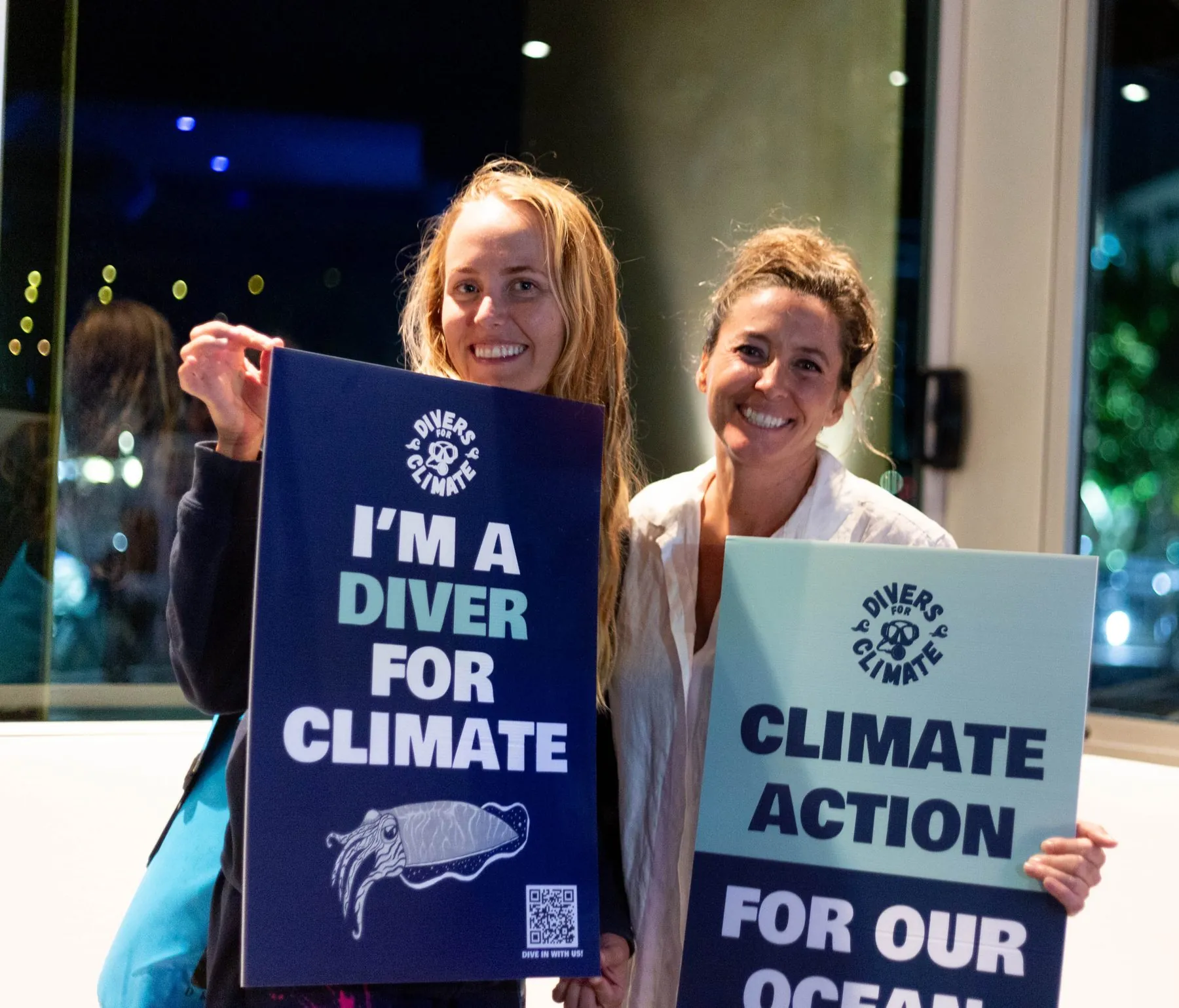 Two community members holding Divers for Climate signs