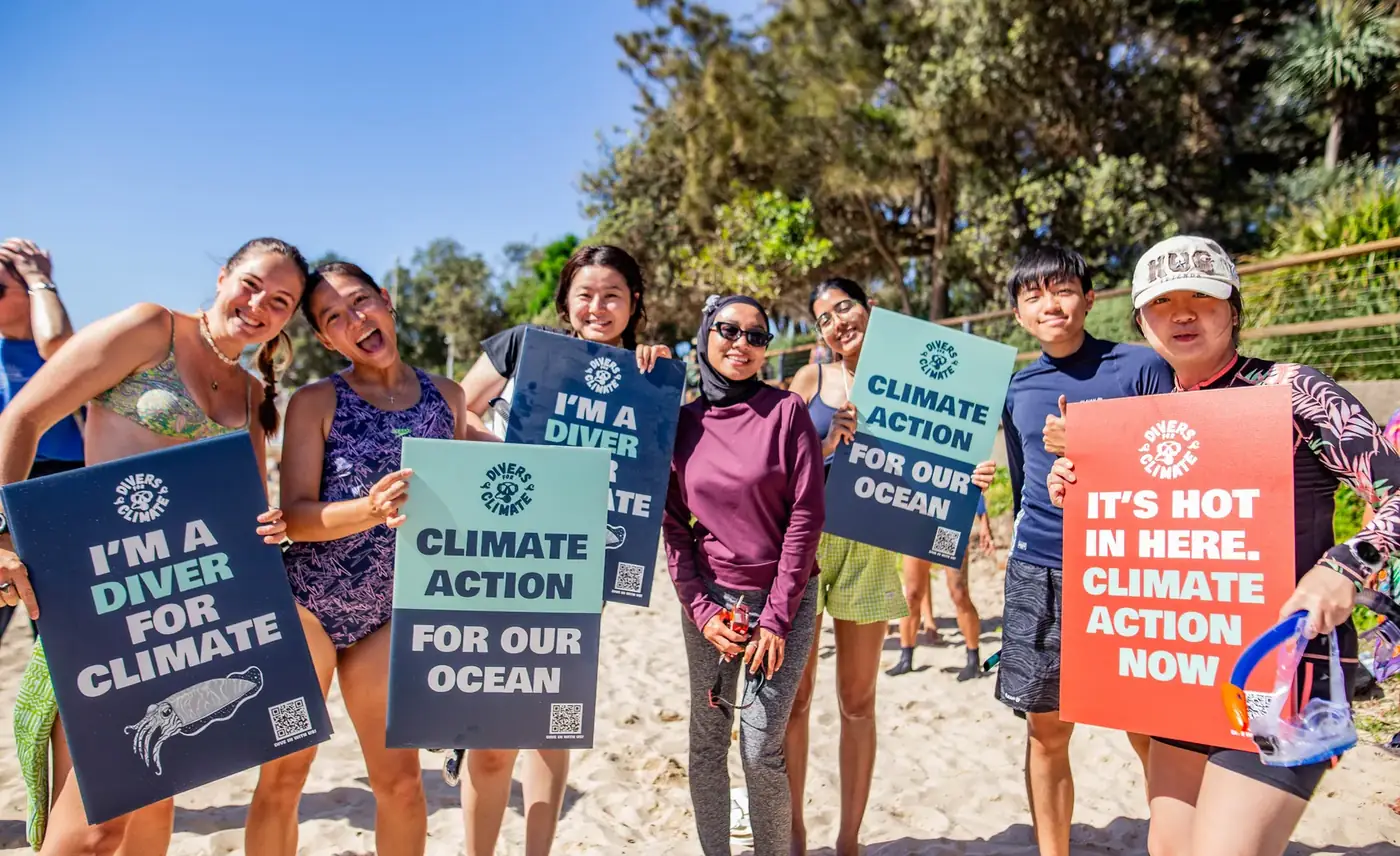 Divers for Climate community members holding climate action signs